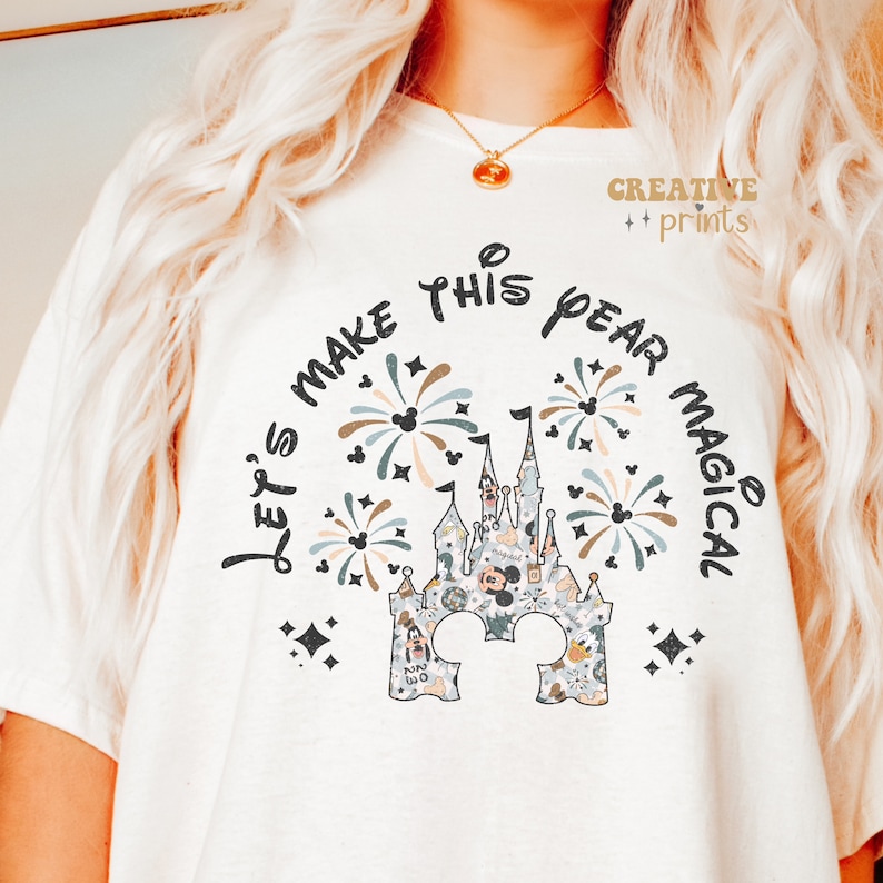 May include: White t-shirt with a black graphic of a castle with fireworks and the text "Let's make this year magical".