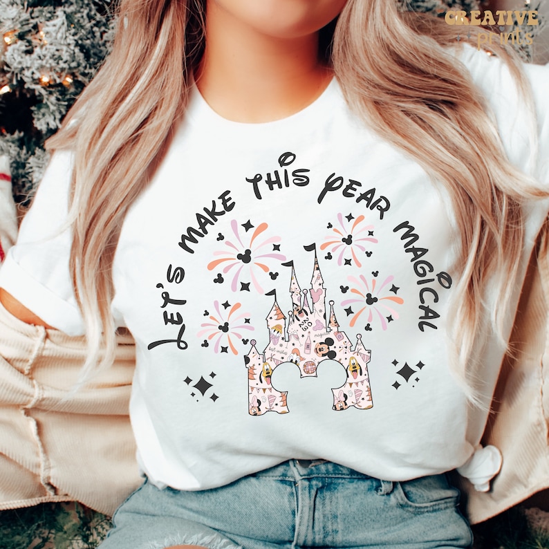 May include: White t-shirt with a black and pink design of a castle with fireworks and the text "Let's make this year magical".