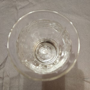 Puede incluir: Un vaso de vidrio transparente para beber con un patr&oacute;n texturizado en los lados. El vaso est&aacute; vac&iacute;o y parece nuevo.