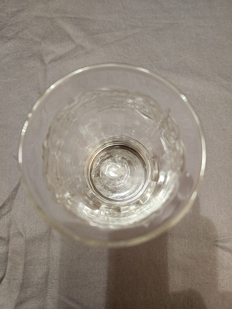 Puede incluir: Un vaso de vidrio transparente para beber con un patr&oacute;n texturizado en los lados. El vaso est&aacute; vac&iacute;o y parece nuevo.