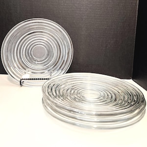 May include: A set of three clear glass plates with concentric circles. The plates are stacked on top of each other.