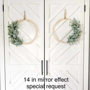 May include: Two 14-inch wood bead wreaths with greenery on a white door with a chevron pattern. The text "14 in mirror effect special request" is at the bottom of the image.