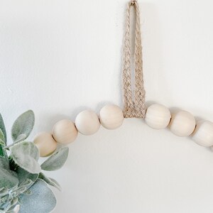May include: A wooden bead garland with a jute rope hanger. The garland is made of natural wood beads and is perfect for adding a touch of rustic charm to your home decor.