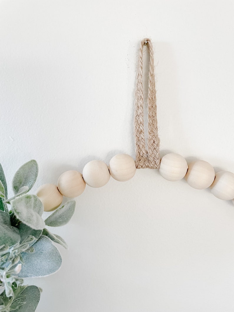 May include: A wooden bead garland with a jute rope hanger. The garland is made of natural wood beads and is perfect for adding a touch of rustic charm to your home decor.