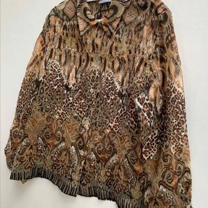 May include: A brown and beige patterned sheer button-up shirt with a collared neckline. The shirt has a long sleeve and a relaxed fit.