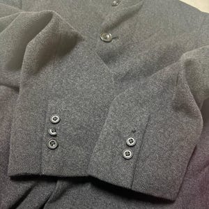 Vintage Mens black wool blend long overcoat featuring a minimalist button up design with stand collar made by A.A.R Durban Urban.Vintage coat ideal for fall and winter streetwear,office wear or layered casual looks.Classic and sleek,perfect for fashion forward individuals seeking timeless urban outerwear.This stylish trench style coat offers comfort,warmth and elegance for everyday city life or formal occasions.