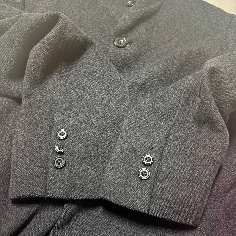 Vintage Mens black wool blend long overcoat featuring a minimalist button up design with stand collar made by A.A.R Durban Urban.Vintage coat ideal for fall and winter streetwear,office wear or layered casual looks.Classic and sleek,perfect for fashion forward individuals seeking timeless urban outerwear.This stylish trench style coat offers comfort,warmth and elegance for everyday city life or formal occasions.