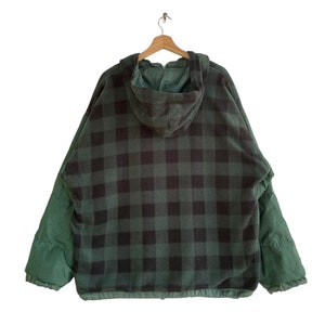 May include: A green and black plaid hooded jacket with a zipper closure. The jacket is made of a soft, fleece-like material.