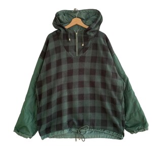 May include: A green and black plaid fleece pullover with a half-zip closure and a drawstring at the bottom. The sleeves are a solid green color.