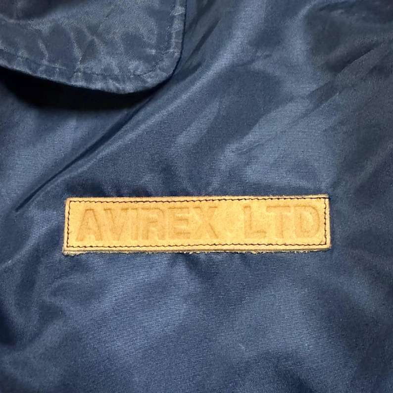 Vintage Avirex MA 1 Bomber Jacket Navy USA Flight Jacket 90s Streetwear Military Jacket Classic Zip Up Nylon Bomber Coat For Men And Women Rare Avirex USA Outerwear Piece With Iconic Back Logo Design.