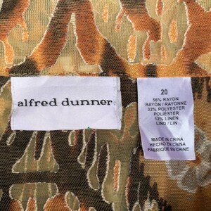 May include: A white tag with black text that reads "alfred dunner" and a size 20 tag with fabric content information. The tag is on a brown and green fabric with a pattern of abstract shapes.