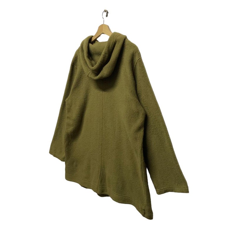 K&ouml;nnte beinhalten: Ein gr&uuml;ner Kapuzenpullover mit einer langen, lockeren Passform. Der Pullover ist aus einem weichen, flauschigen Material.