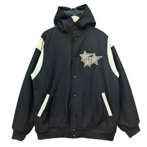 Op de afbeelding: Zwarte varsity-jas met capuchon, witte mouwen en een ster-patch op de borst.