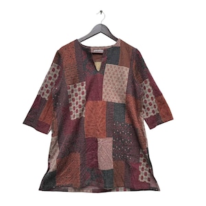 Könnte beinhalten: Eine Patchwork-Tunika mit V-Ausschnitt und Dreiviertelärmeln. Die Tunika ist aus braunem, rotem und beigefarbenem Stoff mit verschiedenen Mustern gefertigt. Der Stoff ist strukturiert und hat einen leicht abgenutzten Look.