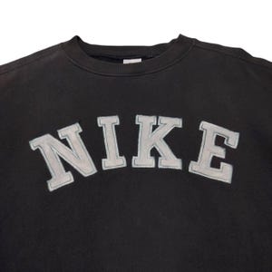 Vintage Nike crewneck sweatshirt featuring iconic spellout logo in classic black, Y2K sportswear style with relaxed unisex fit, perfect for streetwear, casual everyday wear, and vintage Nike collectors worldwide.