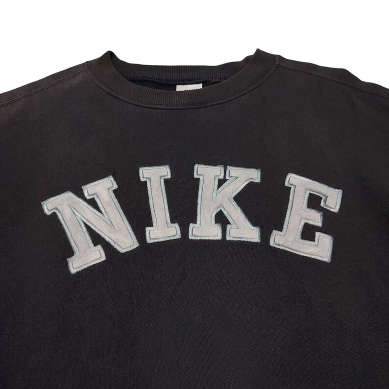 Vintage Nike crewneck sweatshirt featuring iconic spellout logo in classic black, Y2K sportswear style with relaxed unisex fit, perfect for streetwear, casual everyday wear, and vintage Nike collectors worldwide.