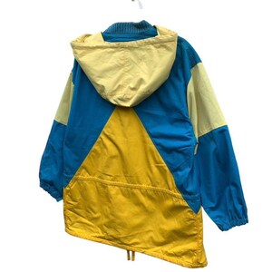 May include: A blue, yellow, and cream colored hooded jacket with a drawstring at the bottom.