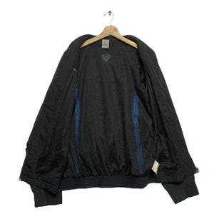 May include: A black windbreaker jacket with blue accents on the inside. The jacket has a zipper closure and a stand-up collar.