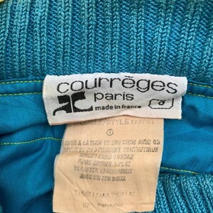 May include: A blue and yellow knitted sweater with a white tag that reads "courr&egrave;ges paris made in france" and "MODEL/STYLE: 15067". The tag also includes washing instructions in French.