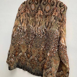 May include: A brown and green patterned shirt with a collared neckline and long sleeves. The shirt has a geometric and animal print design.
