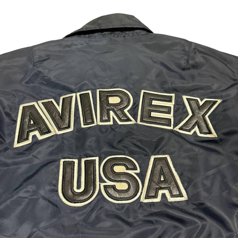 Vintage Avirex MA 1 Bomber Jacket Navy USA Flight Jacket 90s Streetwear Military Jacket Classic Zip Up Nylon Bomber Coat For Men And Women Rare Avirex USA Outerwear Piece With Iconic Back Logo Design.