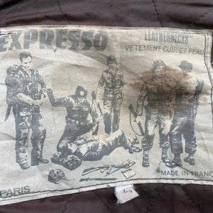 May include: A white patch with black text and a black and white illustration of soldiers. The text reads "EXPRESSO&reg; LEATHERJACKS VETEMENT CUIR ET PEAU PARIS MADE IN FRANCE".