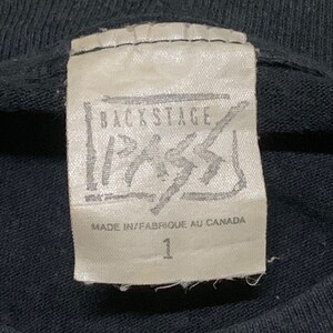 May include: A white tag with black text that reads "Backstage Pass" in a stylized font. The tag also says "Made in/Fabrique au Canada" and has the number "1" printed on it.