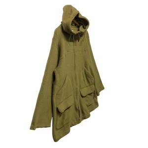 K&ouml;nnte beinhalten: Eine gr&uuml;ne Kapuzenjacke mit Rei&szlig;verschluss und gro&szlig;en Taschen. Die Jacke ist aus einem weichen, flauschigen Material.