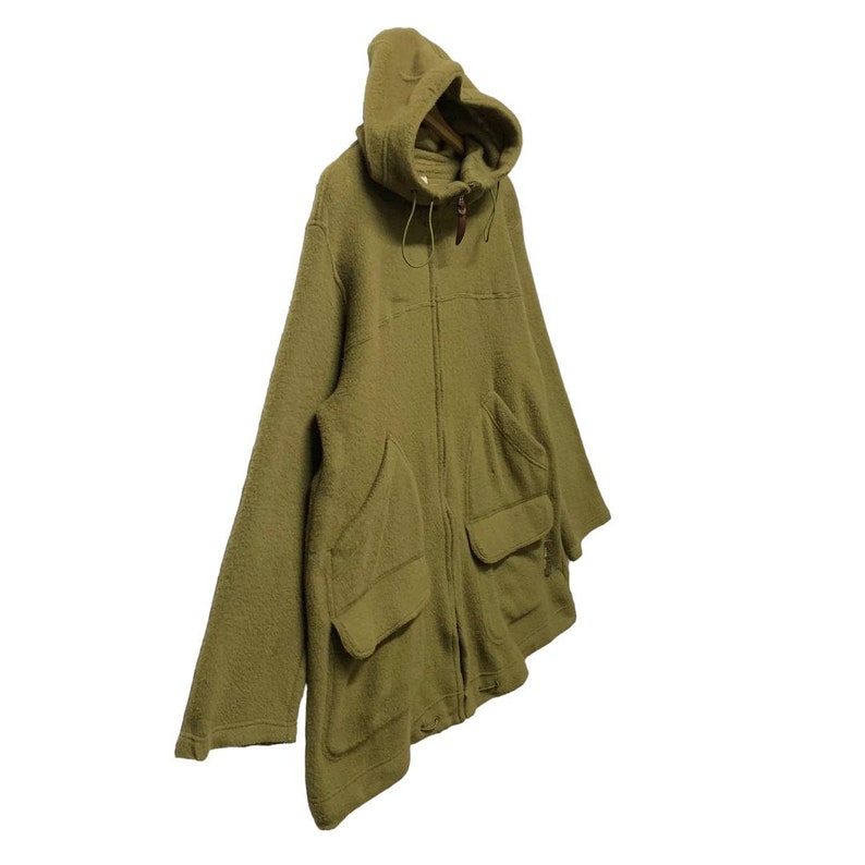 K&ouml;nnte beinhalten: Eine gr&uuml;ne Kapuzenjacke mit Rei&szlig;verschluss und gro&szlig;en Taschen. Die Jacke ist aus einem weichen, flauschigen Material.