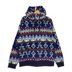 May include: A blue hooded sweatshirt with a colorful geometric pattern. The pattern features red, yellow, green, and white accents. The sweatshirt has a drawstring hood and a kangaroo pocket.
