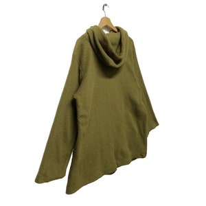 K&ouml;nnte beinhalten: Ein lang&auml;rmeliger, olivgr&uuml;ner Pullover mit einem Rollkragen. Der Pullover ist aus einem weichen, flauschigen Material.