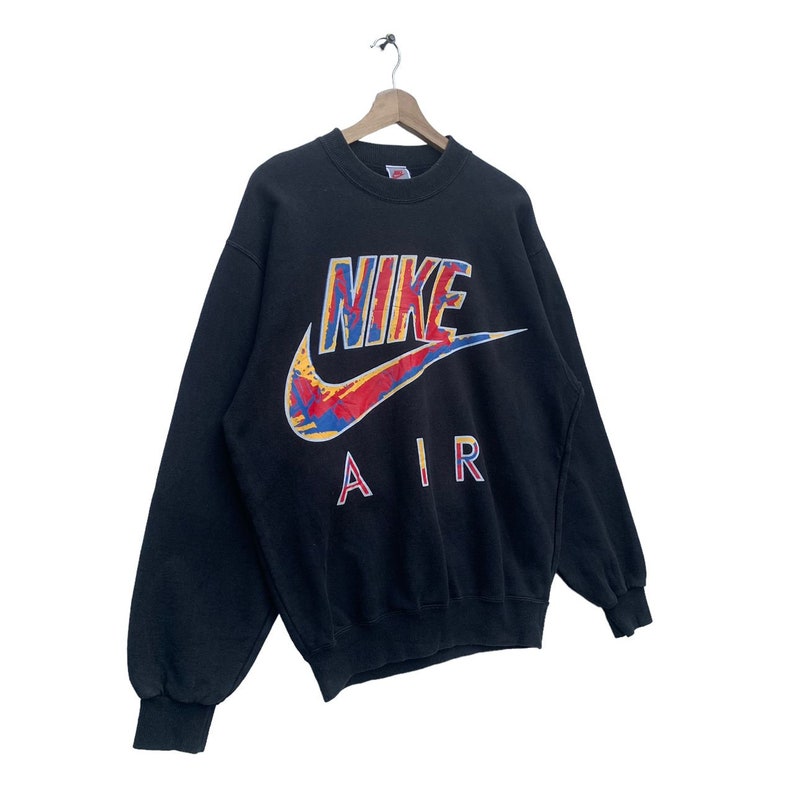 K&ouml;nnte beinhalten: Schwarzer Nike-Sweatshirt mit einem bunten "NIKE AIR"-Logo auf der Vorderseite.