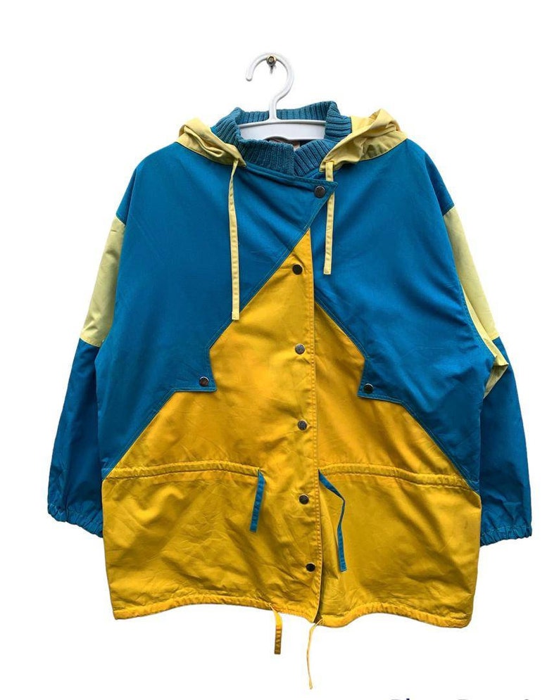 May include: A blue and yellow hooded jacket with a button closure and a drawstring at the bottom.