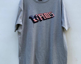 May include: A gray t-shirt with a graphic of the word "Virus" in a 3D style with an American flag design. The graphic has a dripping paint effect.