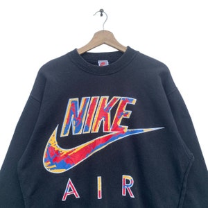 K&ouml;nnte beinhalten: Schwarzer Sweatshirt mit einem gro&szlig;en, bunten Nike Air Logo. Das Logo ist ein stilisierter Swoosh mit dem Wort "NIKE" in fetter Schrift und "AIR" darunter.
