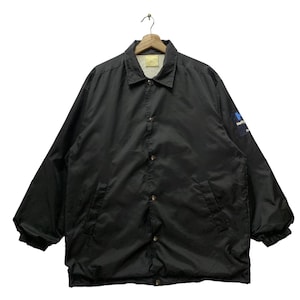 May include: Black nylon coach jacket with a snap closure and a small blue and white patch on the right sleeve that says "Hello Kitty"