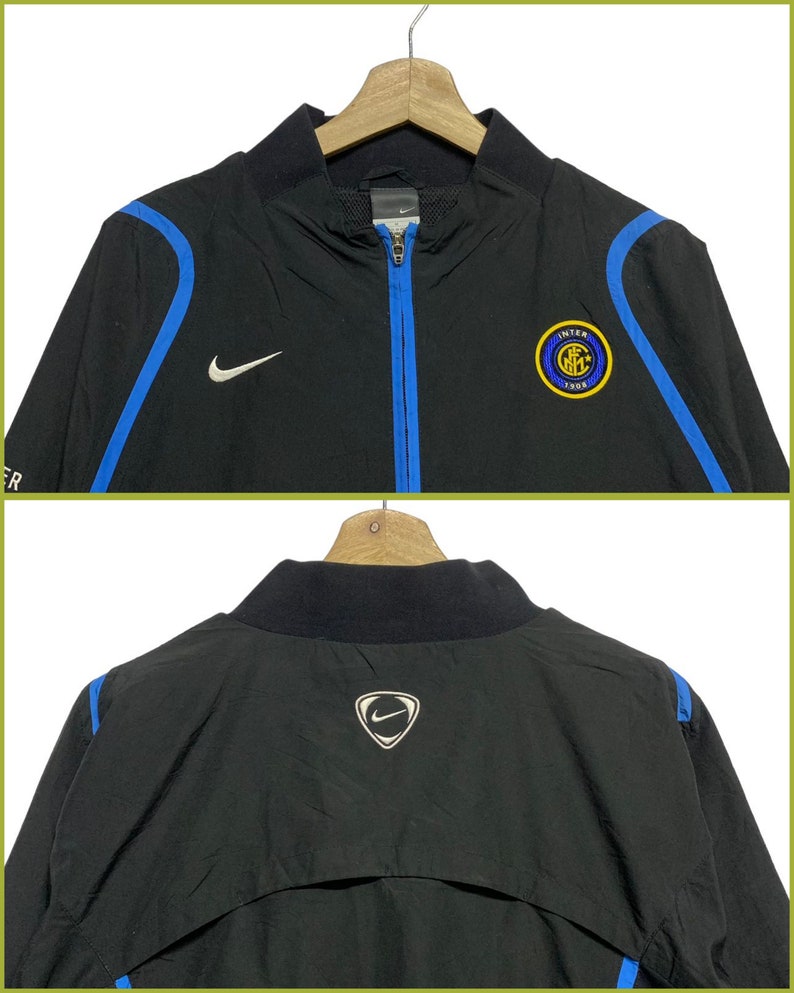 May include: Black Nike windbreaker jacket with blue accents and the Inter Milan logo on the front. The back of the jacket has a Nike swoosh logo.