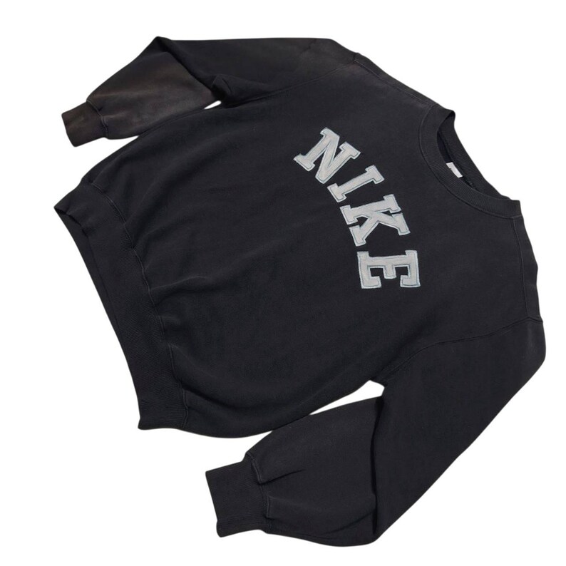 Vintage Nike crewneck sweatshirt featuring iconic spellout logo in classic black, Y2K sportswear style with relaxed unisex fit, perfect for streetwear, casual everyday wear, and vintage Nike collectors worldwide.