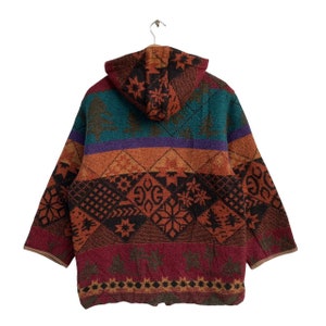May include: A hooded jacket with a colorful, geometric pattern. The jacket is made of a soft, fuzzy material and has a relaxed fit. The pattern features a variety of colors, including red, orange, yellow, green, blue, and purple.