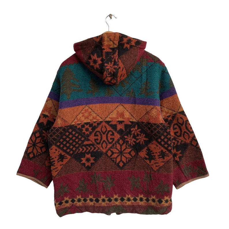 May include: A hooded jacket with a colorful, geometric pattern. The jacket is made of a soft, fuzzy material and has a relaxed fit. The pattern features a variety of colors, including red, orange, yellow, green, blue, and purple.