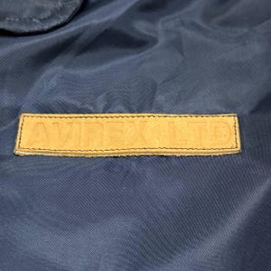 Vintage Avirex MA 1 Bomber Jacket Navy USA Flight Jacket 90s Streetwear Military Jacket Classic Zip Up Nylon Bomber Coat For Men And Women Rare Avirex USA Outerwear Piece With Iconic Back Logo Design.