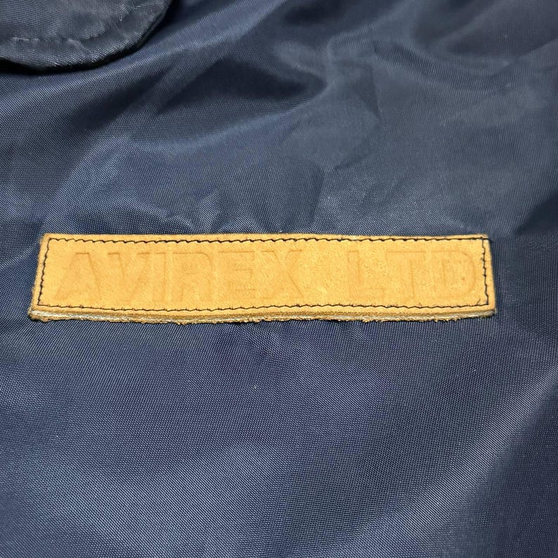 Vintage Avirex MA 1 Bomber Jacket Navy USA Flight Jacket 90s Streetwear Military Jacket Classic Zip Up Nylon Bomber Coat For Men And Women Rare Avirex USA Outerwear Piece With Iconic Back Logo Design.