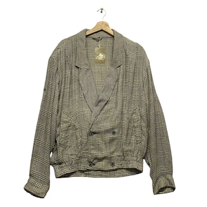 Könnte beinhalten: Eine braune und schwarze karierte Doppelreiherjacke mit langem Kragen und langen Ärmeln. Die Jacke hat zwei Taschen auf der Vorderseite und einen Knopfverschluss.