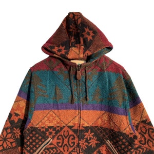 May include: A multi-colored hooded jacket with a zipper closure. The jacket features a geometric pattern with shades of orange, red, green, blue, and purple. The hood is lined with a black and brown pattern.
