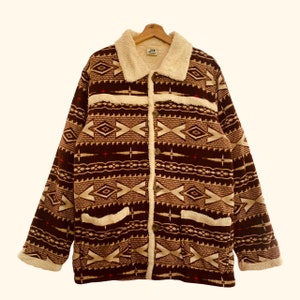 May include: A brown and beige patterned fleece jacket with a sherpa lining. The jacket has a button closure and two pockets.