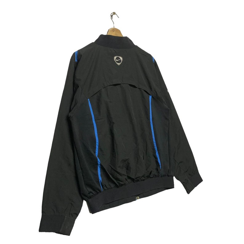 May include: Black windbreaker jacket with blue accents and a Nike swoosh logo on the back.