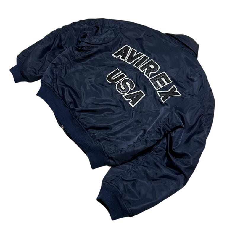 Vintage Avirex MA 1 Bomber Jacket Navy USA Flight Jacket 90s Streetwear Military Jacket Classic Zip Up Nylon Bomber Coat For Men And Women Rare Avirex USA Outerwear Piece With Iconic Back Logo Design.