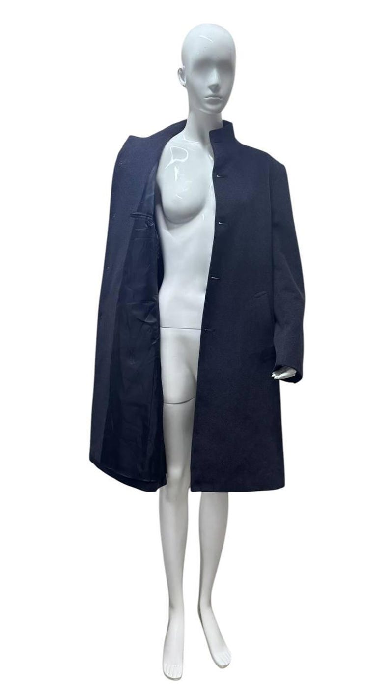 May include: A long, dark blue coat with a mandarin collar and a single button closure. The coat is lined in black.