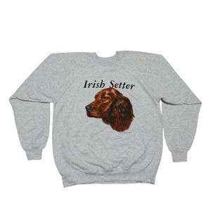 May include: A light gray sweatshirt featuring a detailed illustration of an Irish Setter dog's head in shades of brown. The words "Irish Setter" are printed above the dog image in black.