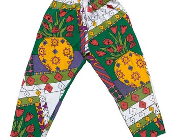 May include: Colorful patterned pants with an elastic waistband. The design features a repeating pattern of tulips in yellow vases, geometric shapes, and stripes in green, purple, red, and white. The pants are made of a lightweight fabric.
